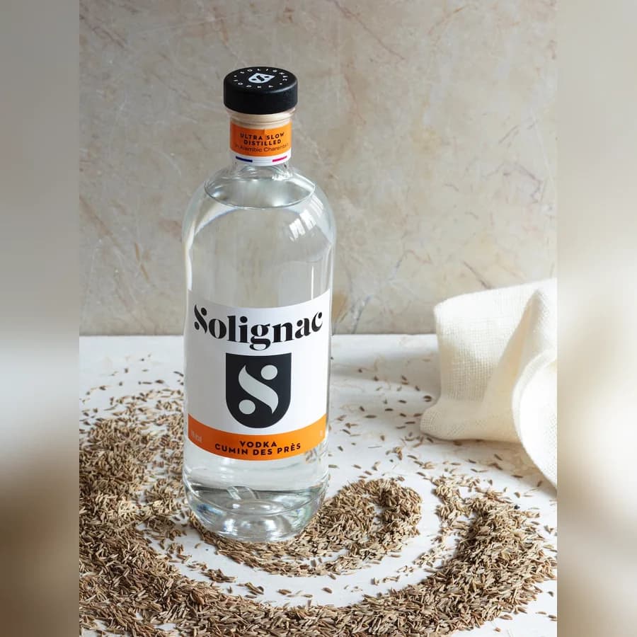 Bouteille de vodka Solignac Cumin des Prés entourée de graines de carvi